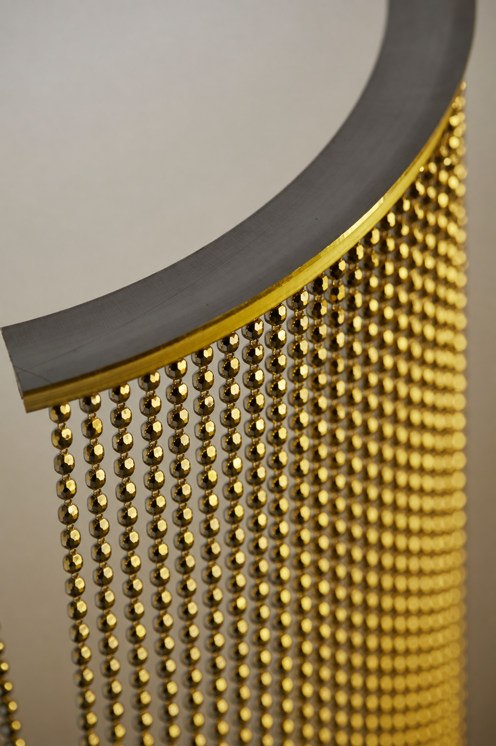 Nickel Plated or Aluminum or silver colored Faceted metal ball chain hanging vertically on circular track and yellow light shining onto the system